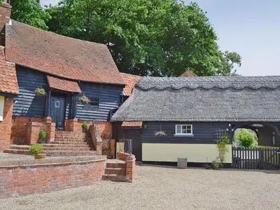 an old house with a black roof and a garage at Lake House Cottage in Finchingfield