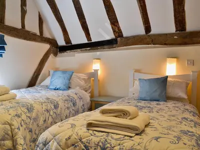 two twin beds in a room with beams at Walnut Cottage in Sproughton