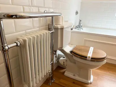 a bathroom with a toilet with a wooden seat and a radiator at Luxury 1 Bedroom Apartment in Southend w Parking in Southend-on-Sea
