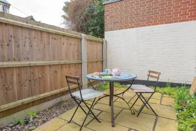 a patio table with two chairs and a pink tea set at Pebble House, Aldeburgh in Aldeburgh