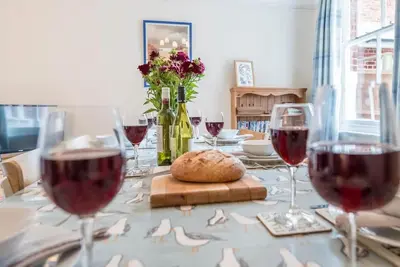 a table with wine glasses and a bread on it at Pebble House, Aldeburgh in Aldeburgh