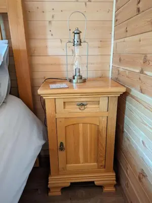 a small wooden table with a lamp on top of it at Meadow Lodge in Billericay