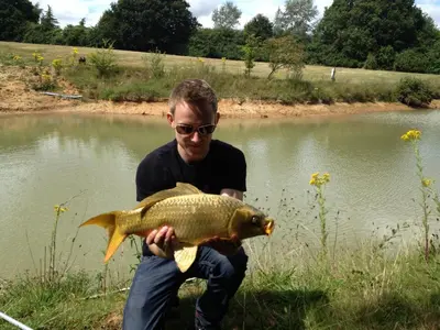 a man holding a fish in front of a pond at Meadow Lodge in Billericay