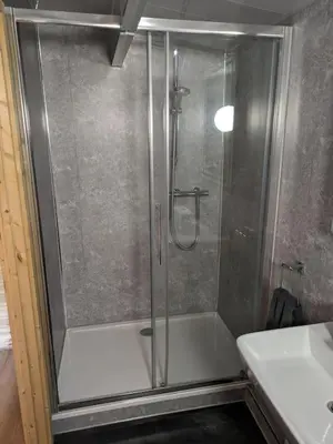 a shower with a glass door in a bathroom at Meadow Lodge in Billericay