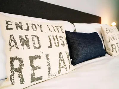 a bed with a pillow that says burn me and usayan at Cannon Corner by The Suffolk Cottage Collection in Aldeburgh