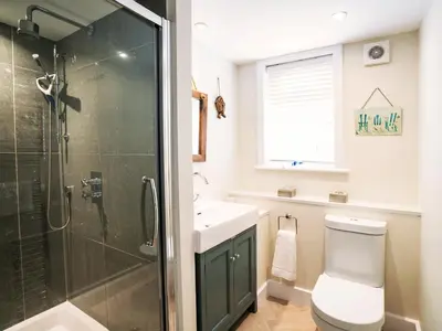 a bathroom with a shower and a toilet and a sink at Cannon Corner by The Suffolk Cottage Collection in Aldeburgh