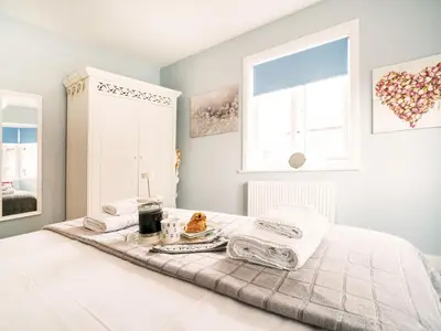 a bedroom with a bed with a tray of food on it at Cannon Corner by The Suffolk Cottage Collection in Aldeburgh