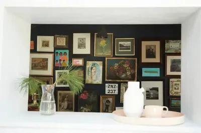 a wall filled with pictures and a vase on a shelf at The Skyroom in Rendham
