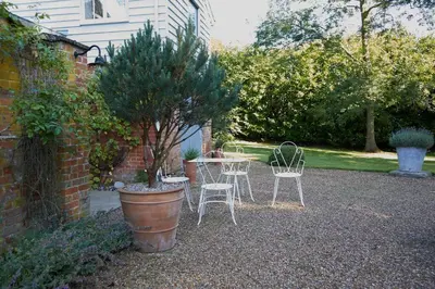 a patio with two chairs and a table and a tree at The Skyroom in Rendham
