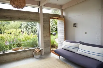 a living room with a blue couch and a large window at The Skyroom in Rendham