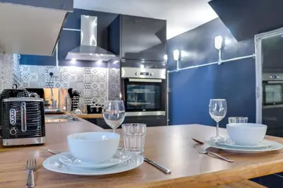 a kitchen with a wooden table with plates and wine glasses at Studio Apartments in Southend in Southend-on-Sea