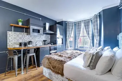 a bedroom with blue walls and a bed and a kitchen at Studio Apartments in Southend in Southend-on-Sea
