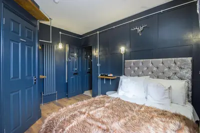 a bedroom with blue walls and a bed with white pillows at Studio Apartments in Southend in Southend-on-Sea