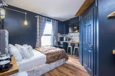 a bedroom with blue walls and a bed and a kitchen at Studio Apartments in Southend in Southend-on-Sea