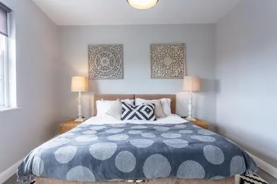 a bedroom with a blue and white bed with two lamps at St Johns Apartments & Studios Southend in Southend-on-Sea