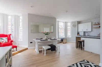 a living room with a table and a red chair at St Johns Apartments & Studios Southend in Southend-on-Sea