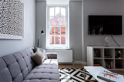 a living room with a gray couch and a window at St Johns Apartments & Studios Southend in Southend-on-Sea