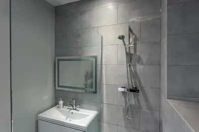 a bathroom with a shower and a sink and a mirror at St Johns Apartments & Studios Southend in Southend-on-Sea