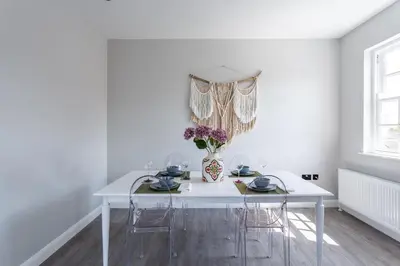 a white dining room table with chairs and a vase of flowers at St Johns Apartments & Studios Southend in Southend-on-Sea
