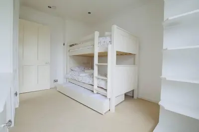a white bedroom with white bunk beds in it at Exquisite location close to the sea! in Frinton-on-Sea