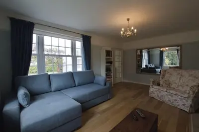 a living room with a blue couch and a chair at Exquisite location close to the sea! in Frinton-on-Sea