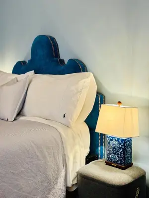 a bed with a blue headboard and a table with a lamp at Stunning designer House in excellent city location in Cambridge