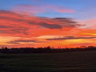 a sunset in a field with a red sky at Gladwyns Farm Lodge in Thaxted