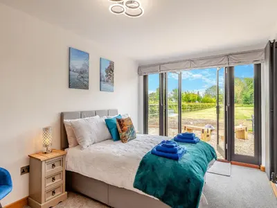 a bedroom with a bed and a large window at Gladwyns Farm Lodge in Thaxted