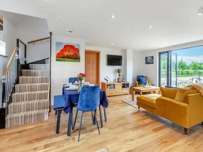 a living room with a dining room table and a couch at Gladwyns Farm Lodge in Thaxted