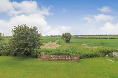 a wooden bench in the middle of a field at Charming dog friendly cottage in rural Suffolk in Eye
