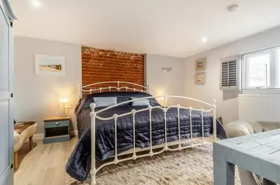 a bedroom with a bed and a brick wall at Charming dog friendly cottage in rural Suffolk in Eye