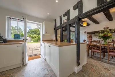 a kitchen with white cabinets and a dining room with a table at Rural perfection in Constable Country - Beachams Cottage in Colchester