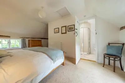 a bedroom with a large bed and a blue chair at Rural perfection in Constable Country - Beachams Cottage in Colchester