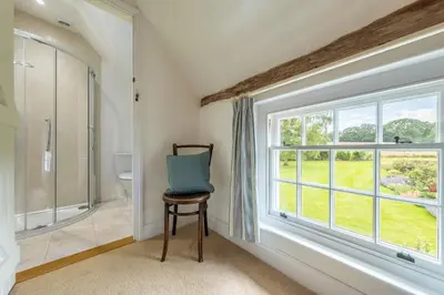 a bathroom with a window and a chair and a shower at Rural perfection in Constable Country - Beachams Cottage in Colchester