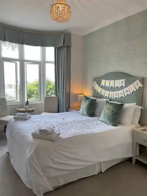 a bedroom with a large white bed with a large window at Beaches Guest House in Southend-on-Sea