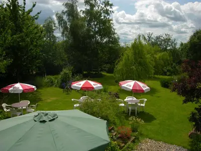 a group of tables with umbrellas in a garden at Six Bells Inn in Bardwell