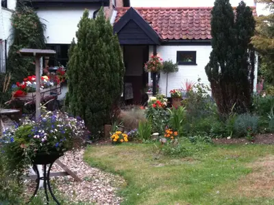 a garden in front of a house with flowers at Six Bells Inn in Bardwell