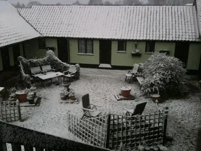 a house with a yard covered in snow at Six Bells Inn in Bardwell