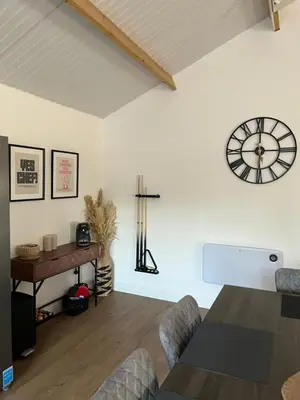 a living room with a table and a clock on the wall at 3 Bed Barn in Cambridge next to Anglesey Abbey in Cambridge