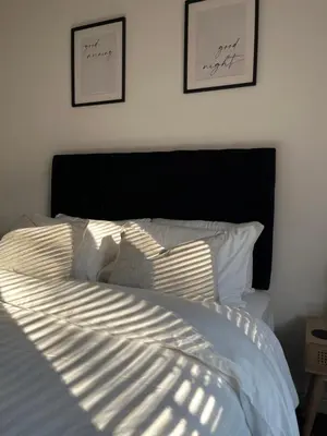 a bed with white sheets and two pictures on the wall at 3 Bed Barn in Cambridge next to Anglesey Abbey in Cambridge
