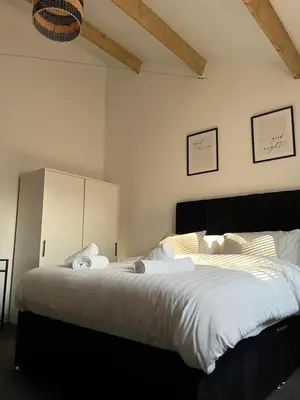 a bedroom with a large bed with white sheets at 3 Bed Barn in Cambridge next to Anglesey Abbey in Cambridge