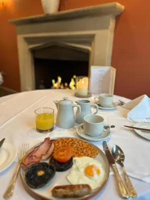 a breakfast plate of eggs and beans on a table with a fireplace at Ravenwood Hall Hotel in Bury Saint Edmunds