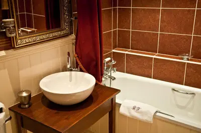 a bathroom with a bowl sink and a bath tub at Ravenwood Hall Hotel in Bury Saint Edmunds