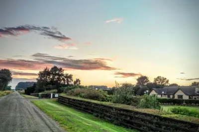 a dirt road with a sunset in the background at A great country escape in Hockwold cum Wilton