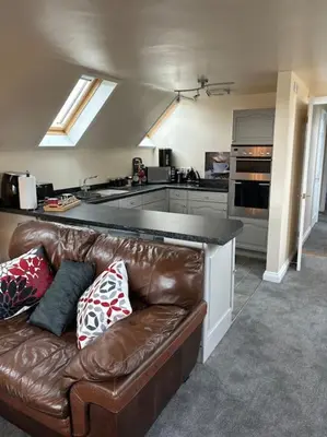 a living room with a brown leather couch in a kitchen at A great country escape in Hockwold cum Wilton