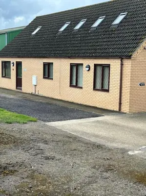 a brick building with windows and a black roof at A great country escape in Hockwold cum Wilton