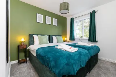 a bedroom with a large bed with green walls at Entire House - Contractor's, Families & More in Little Wymondley