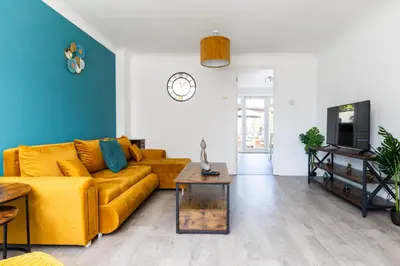a living room with a yellow couch and a table at Entire House - Contractor's, Families & More in Little Wymondley