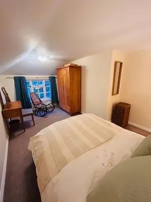 a bedroom with a bed and a chair and a window at Cottage K in Hinxton