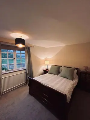 a bedroom with a large bed and a window at Cottage K in Hinxton